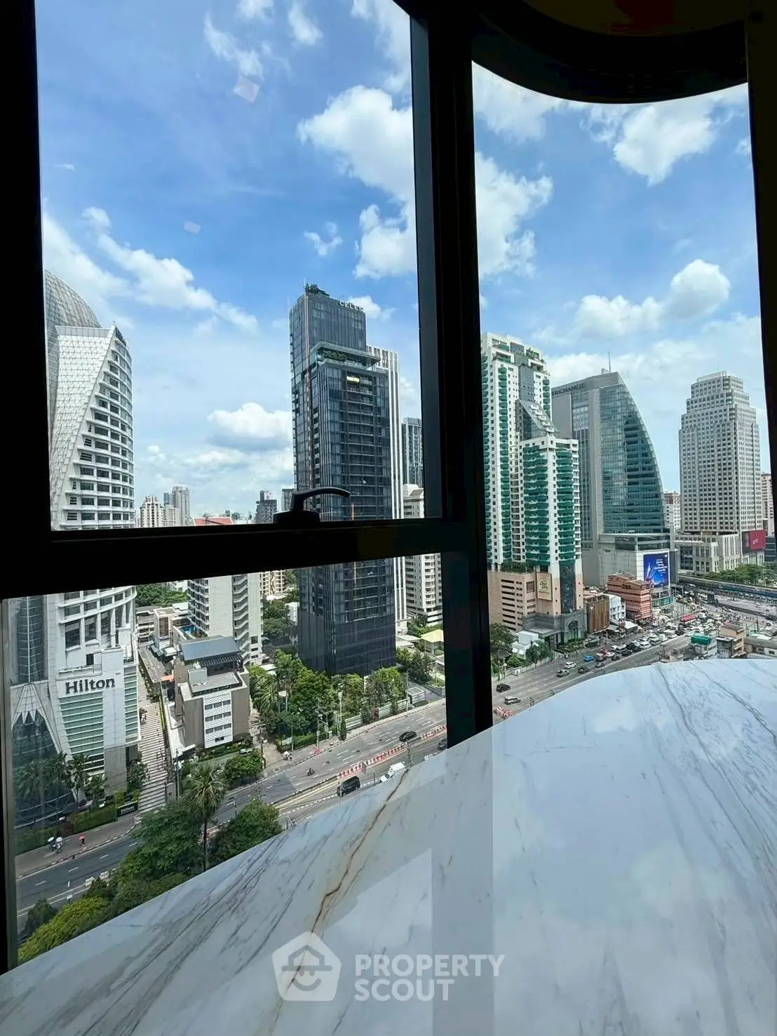 Stunning cityscape view from high-rise window with modern skyscrapers and blue sky.