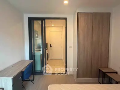Modern bedroom with built-in wardrobe and study desk, featuring a view into a laundry area with washer and dryer.