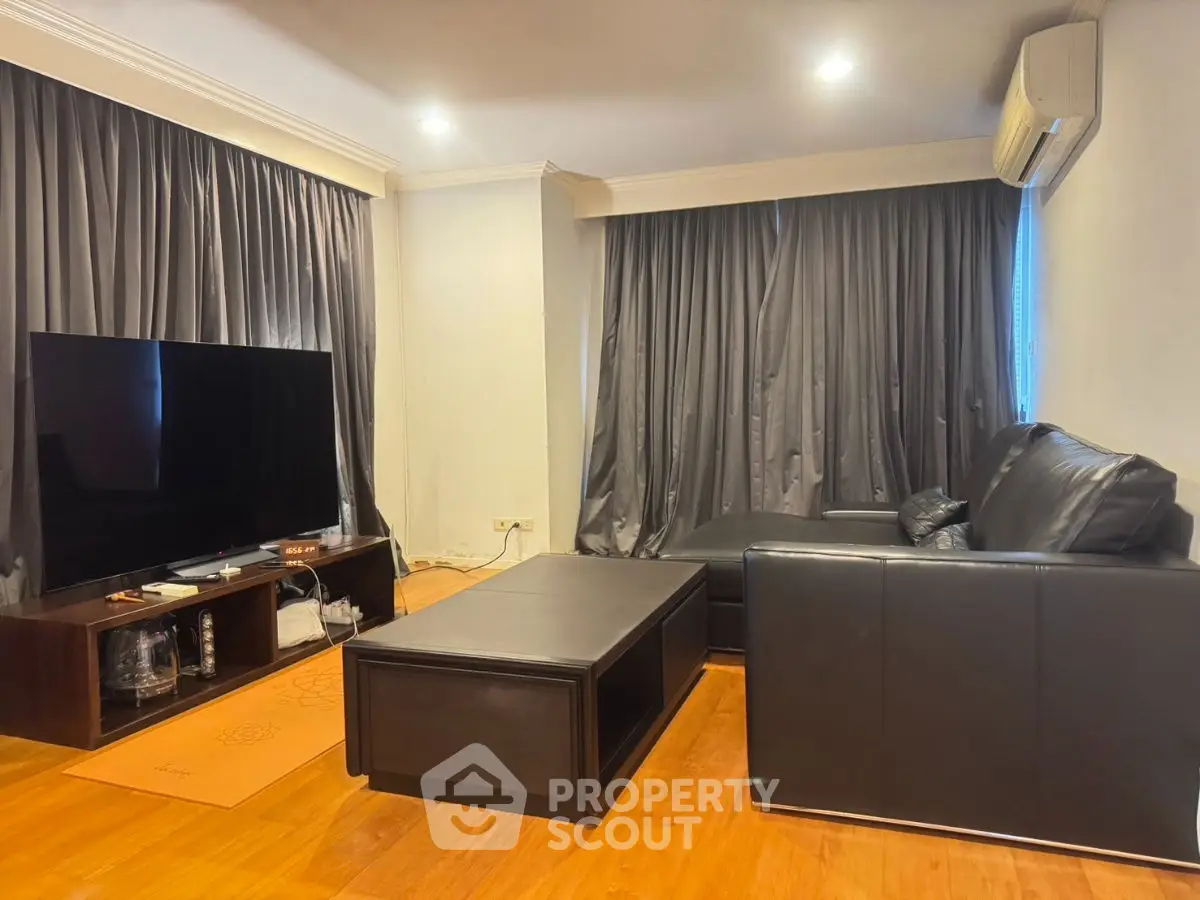 Spacious living room with modern black leather sofa and large TV setup.