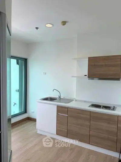 Modern kitchen with sleek cabinetry and dual sink in bright apartment