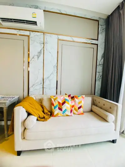 Stylish living room with modern sofa and colorful pillows, marble accent wall, and elegant decor.
