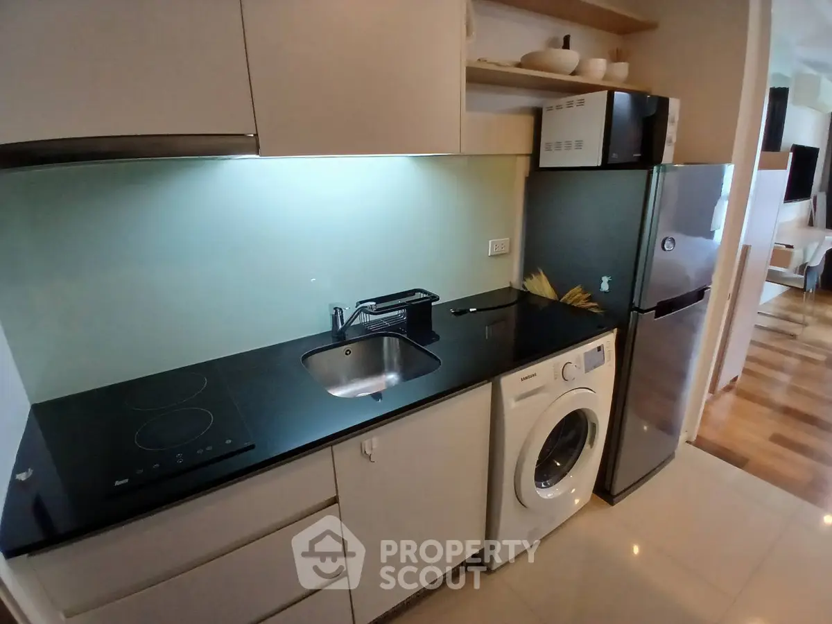 Modern kitchen with sleek appliances and washing machine in compact layout