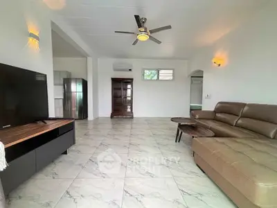 Spacious living room with modern furniture and ceiling fan, featuring open layout and natural light.