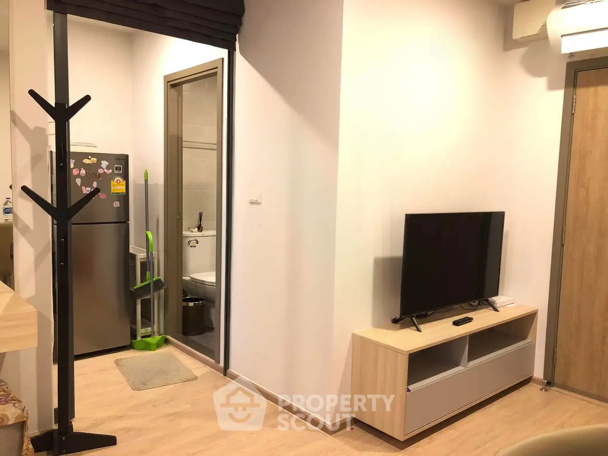 Modern apartment interior with sleek kitchen and cozy living area featuring a flat-screen TV and stylish decor.