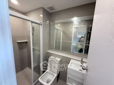 Modern bathroom with sleek shower and compact fixtures in contemporary apartment.