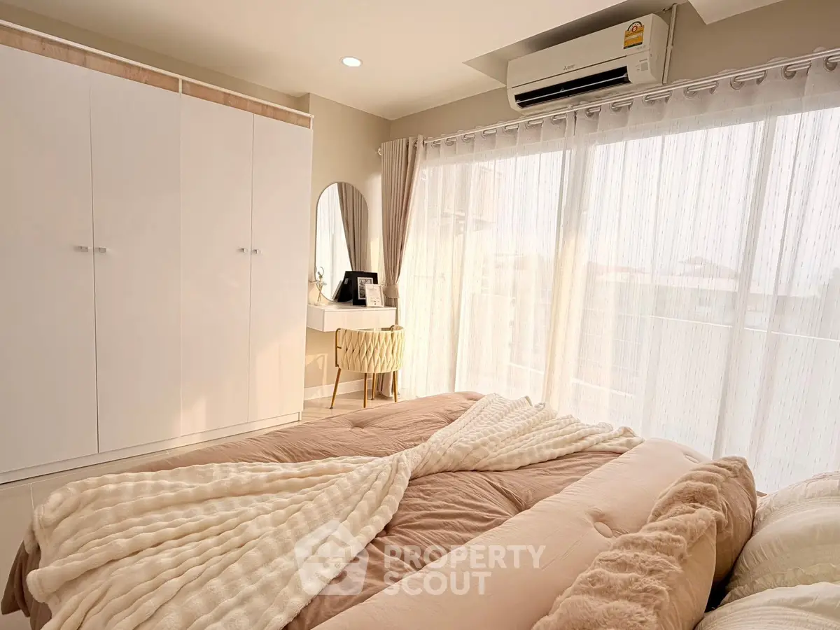 Cozy bedroom with soft lighting, elegant decor, and large windows for natural light.