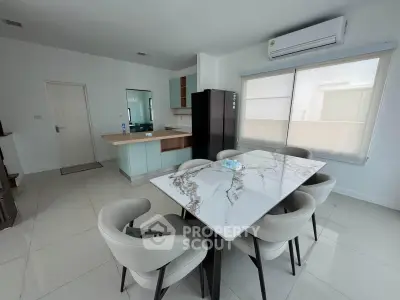 Modern dining area with marble table and sleek kitchen in open layout apartment.