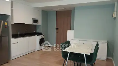 Modern kitchen with sleek appliances and dining area in open layout apartment.