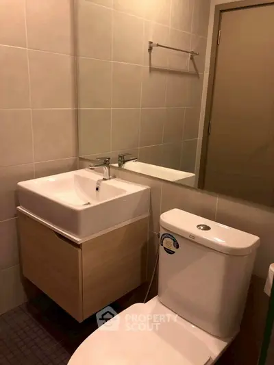 Modern bathroom with sleek fixtures and neutral tiles, featuring a stylish sink and toilet.