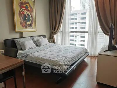 Modern bedroom with large windows and city view, featuring stylish decor and cozy bedding.