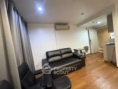 Modern living room with sleek black furniture and wooden flooring