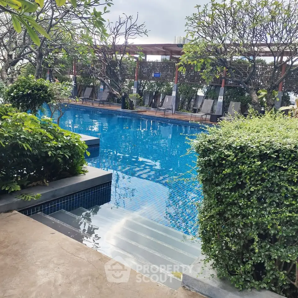 Luxurious outdoor pool with lush greenery and elegant seating area, perfect for relaxation.