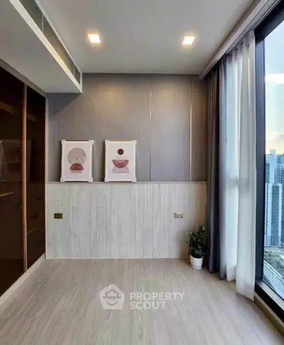 Modern living room with large windows and city view, featuring stylish decor and natural light.