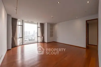Spacious empty living room with wooden flooring and city view, perfect for customization.