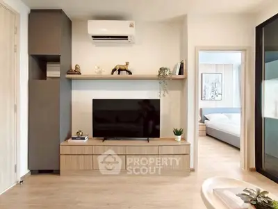 Modern living room with sleek TV unit and view into cozy bedroom