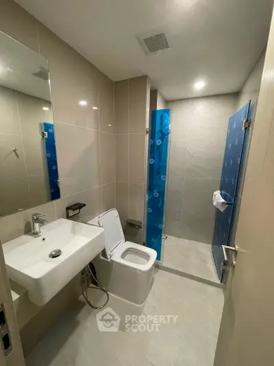 Modern bathroom with sleek fixtures and glass shower enclosure in contemporary apartment.