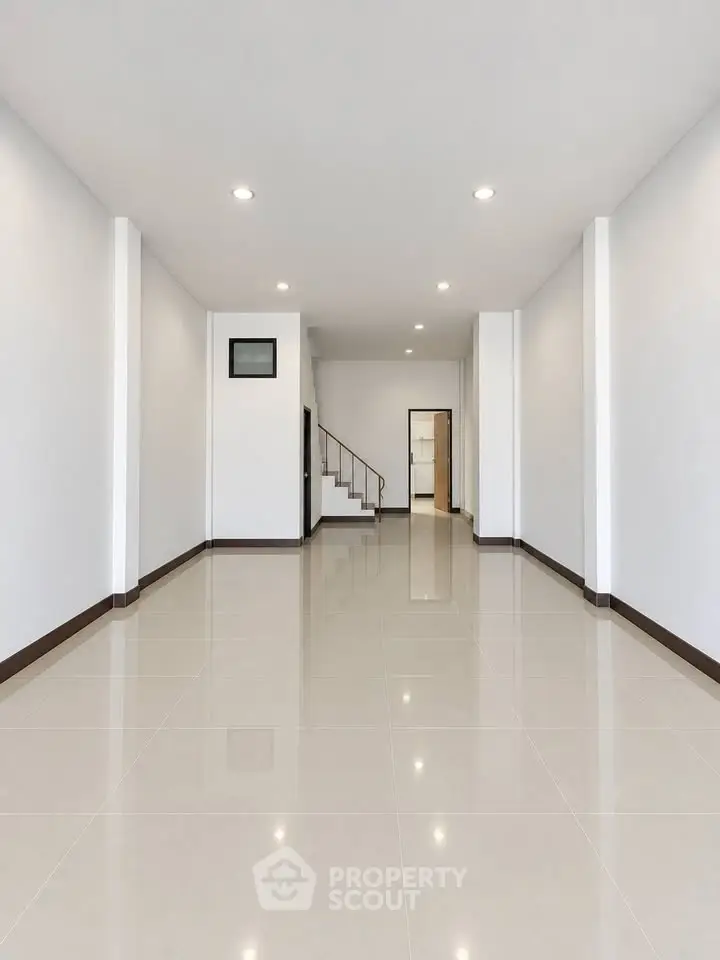 Spacious modern living room with sleek tile flooring and recessed lighting, perfect for contemporary living.