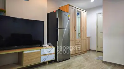Modern living room with sleek TV unit and stainless steel fridge in cozy apartment.