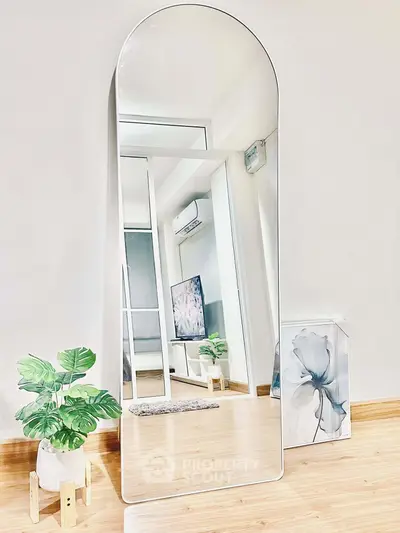 Modern living room with stylish mirror and indoor plant, showcasing minimalist decor and wooden flooring.