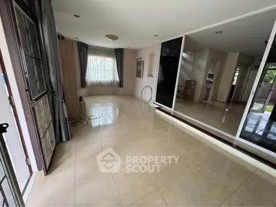 Spacious tiled room with large windows and mirrored wall, perfect for versatile living space.
