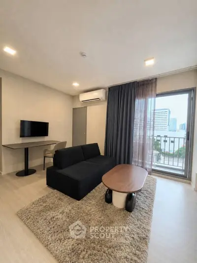 Modern living room with sleek black sofa, stylish coffee table, and city view balcony in a contemporary apartment.