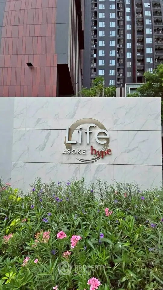 Modern condominium exterior with lush garden and stylish building signage.