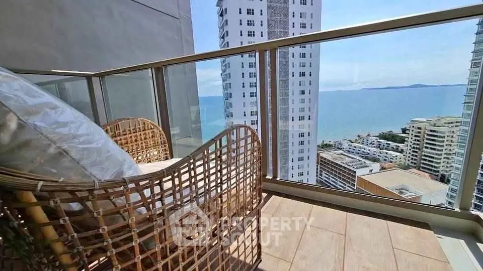Stunning balcony view with ocean backdrop and modern high-rise buildings, perfect for relaxation.