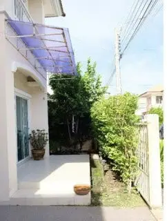 Charming residential entrance with lush greenery and modern awning, perfect for welcoming guests.
