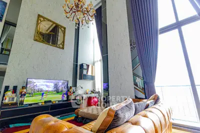 Luxurious living room with high ceilings and elegant decor, featuring a large window with natural light.