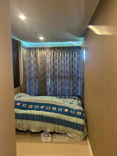 Cozy bedroom with modern decor and large window draped with elegant curtains.