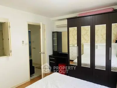 Spacious bedroom with mirrored wardrobe and modern furnishings.