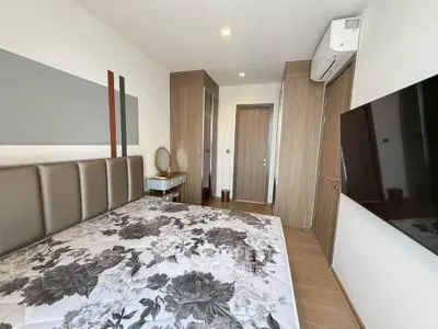 Modern bedroom with stylish decor, large TV, and air conditioning in a contemporary apartment.