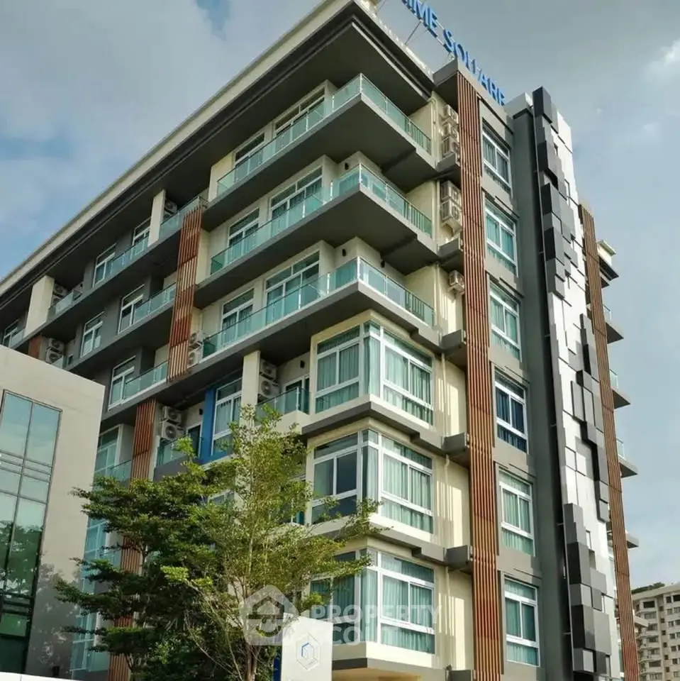 Modern multi-story residential building with large windows and balconies in urban setting.