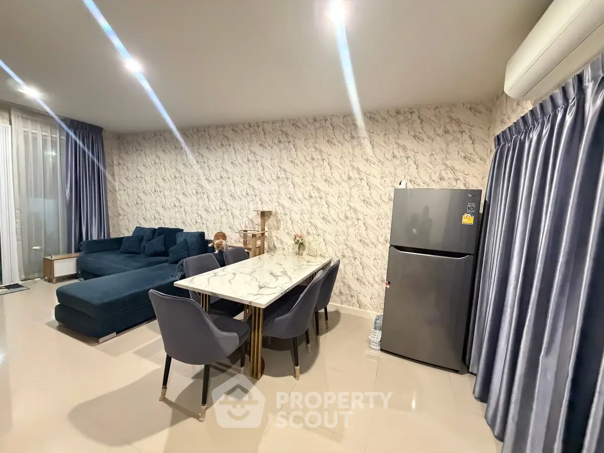 Modern living room with elegant marble dining table and cozy blue sofa, featuring stylish curtains and a sleek refrigerator.