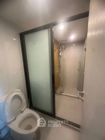 Modern bathroom with glass shower enclosure and toilet in sleek design.