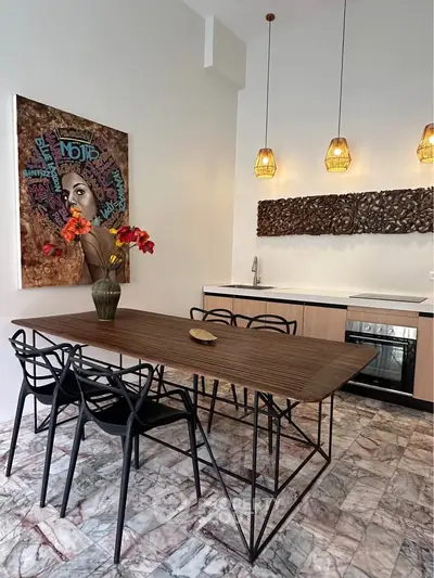 Modern kitchen with stylish dining area, featuring unique artwork and elegant lighting fixtures.