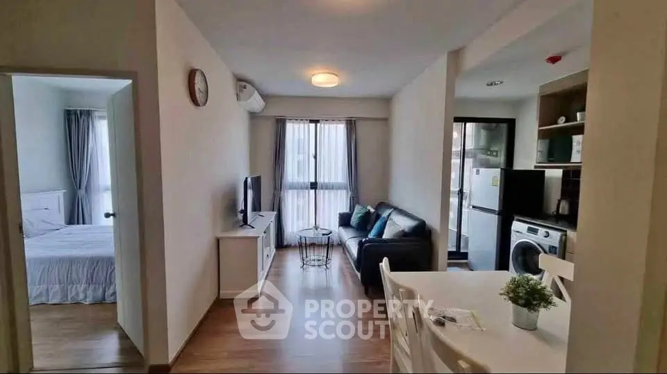 Modern open-plan living room with kitchen and bedroom view, featuring stylish furniture and natural light.