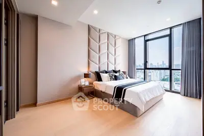 Luxurious bedroom with city view and modern decor in high-rise apartment.