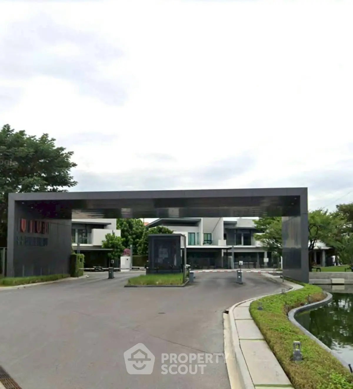 Modern gated community entrance with sleek design and lush greenery