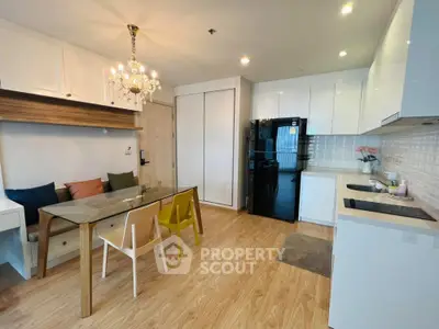 Modern kitchen with dining area, featuring sleek cabinetry and elegant lighting in a cozy apartment.