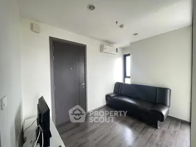 Modern minimalist living room with sleek black sofa and wall-mounted TV.