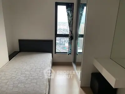 Cozy bedroom with city view, featuring a bed and mirrored wardrobe.