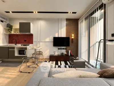 Modern living room with open kitchen, stylish decor, and natural light from large windows.