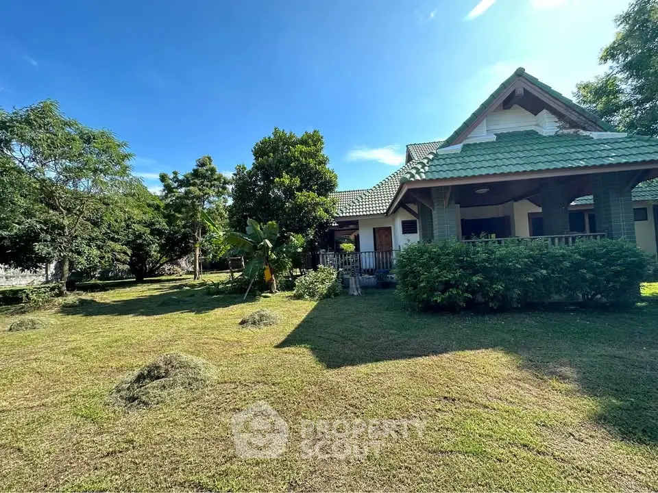 Charming countryside home with lush garden and traditional architecture under a clear blue sky.