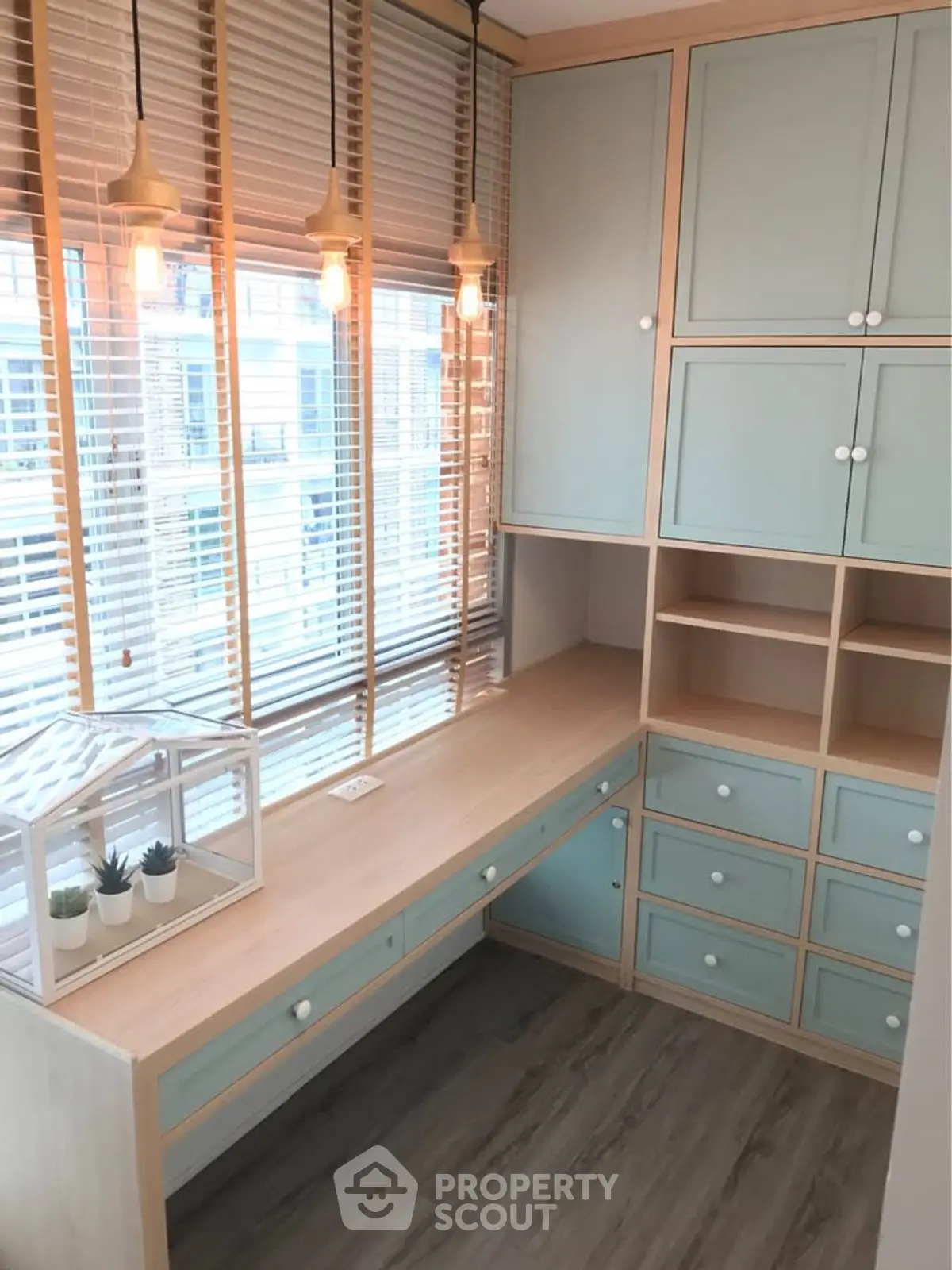 Charming study room with built-in desk and cabinets, featuring stylish pendant lighting and large windows.