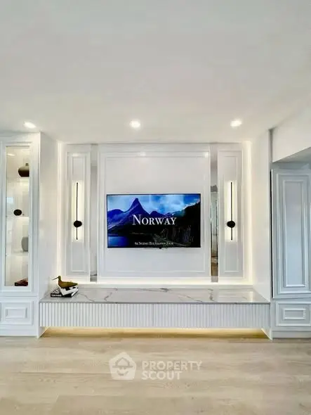 Elegant living room with built-in TV, modern lighting, and sleek white cabinetry.