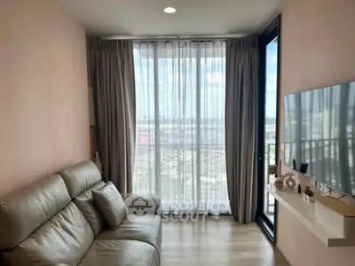 Modern living room with large window and city view, featuring a comfortable sofa and wall-mounted TV.