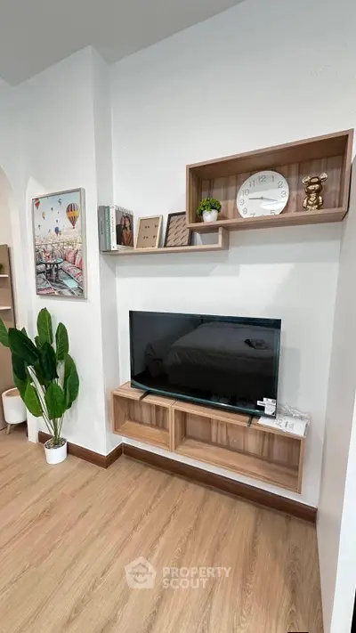 Modern living room with stylish wooden shelves and TV, featuring elegant decor and a cozy atmosphere.