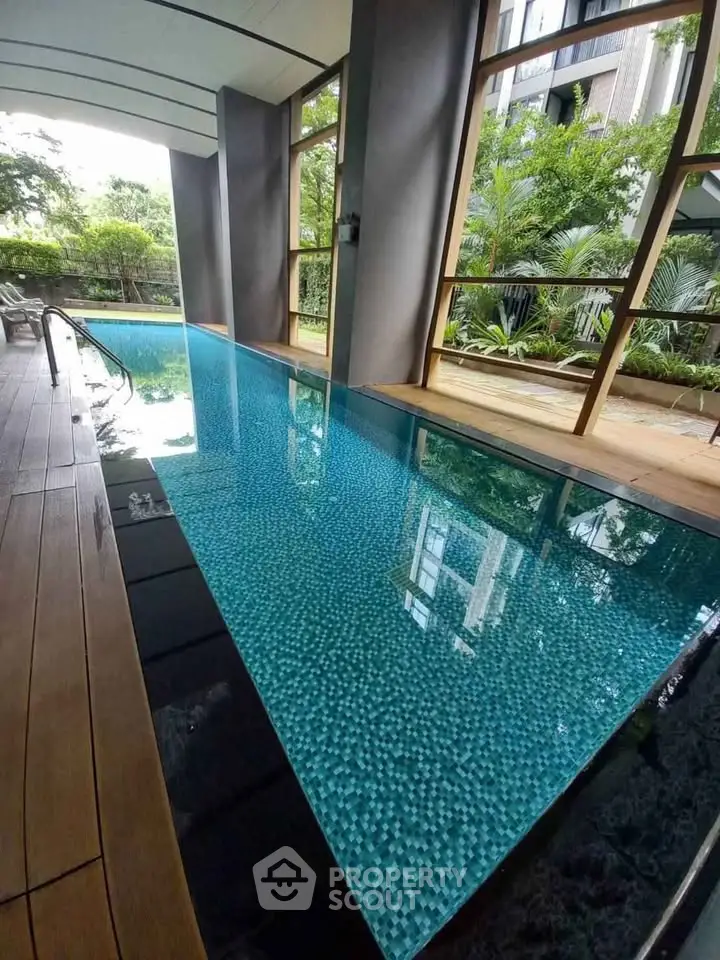 Luxurious indoor pool with serene garden view in modern residential building.