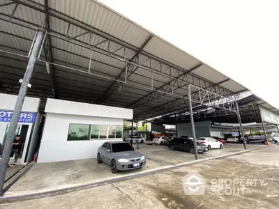 Spacious covered parking area with multiple cars and industrial roofing.